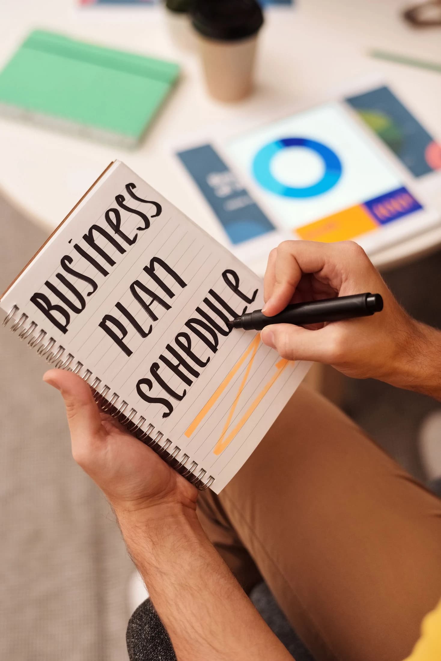 Hands writing a business plan and schedule in a notebook