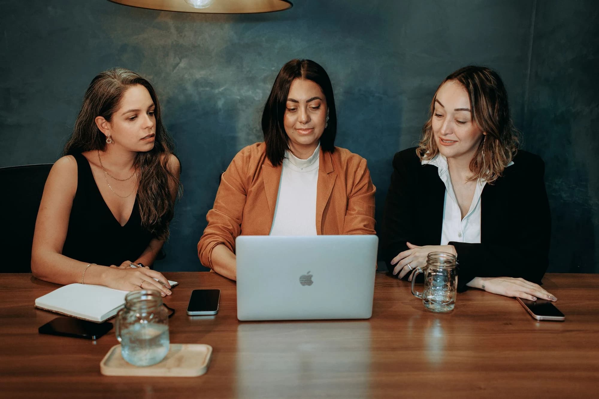 Three women reviewing work together at a cafe table