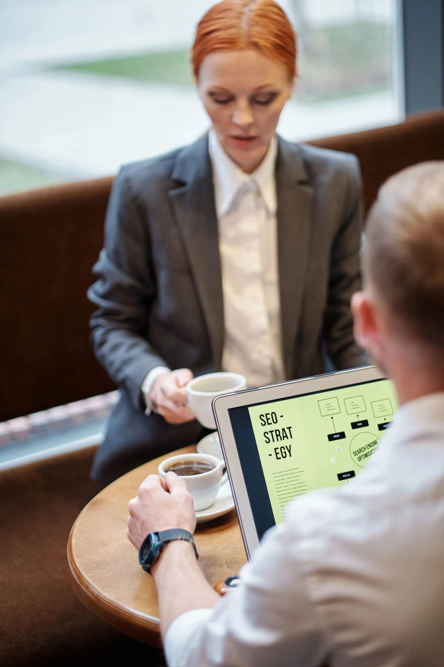 Two people discussing work over a laptop in a cafe