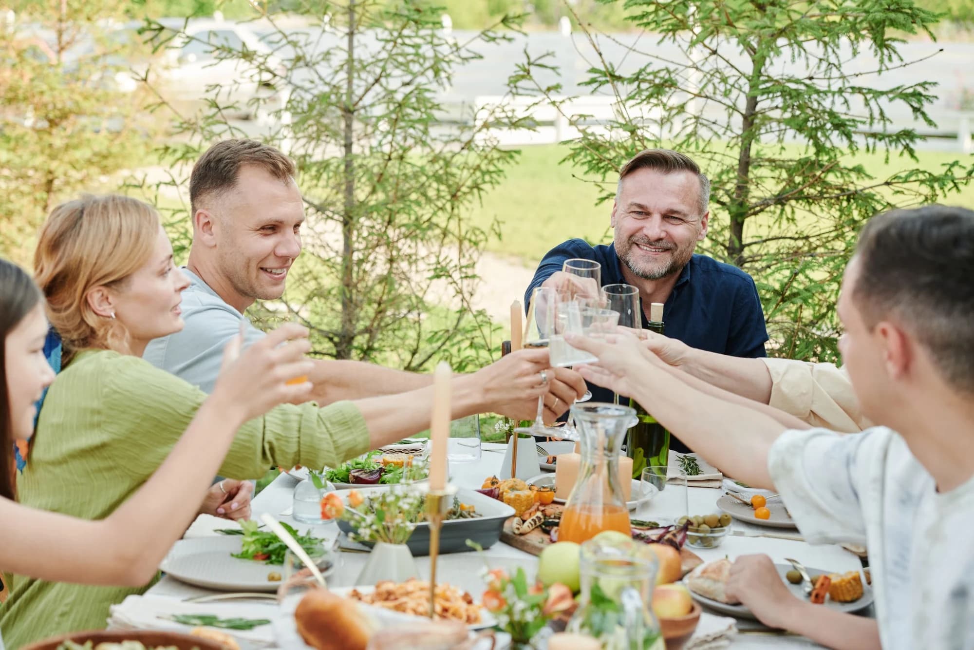 Friends raising a toast over a long outdoor dinner table